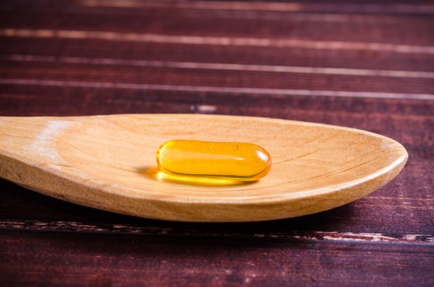 Fish oil on wooden spoon with wooden background