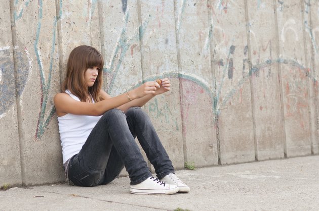 Cute sad teenage girl sitting alone