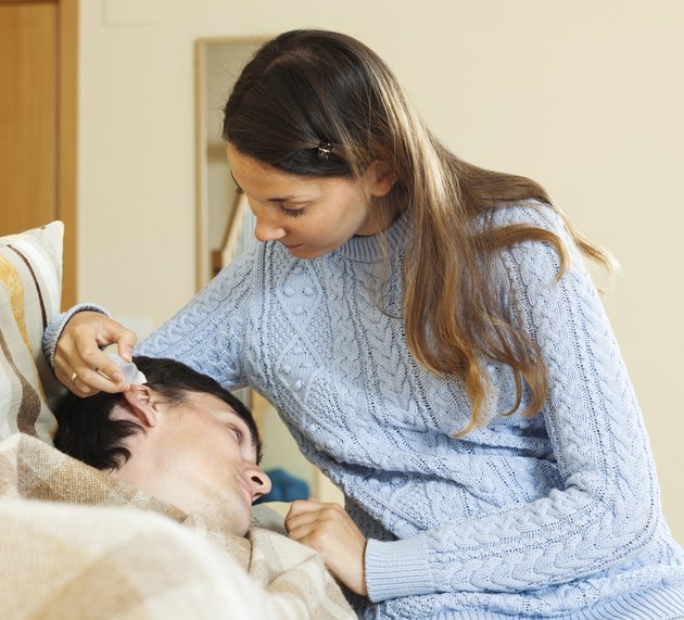 Young woman dripping ear drops to man