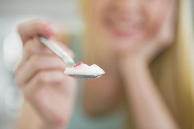 closeup on young woman giving spoon with yogurt