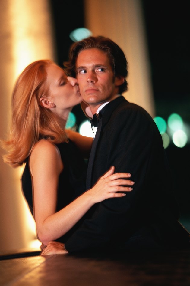 Woman kissing man on cheek, man turning head
