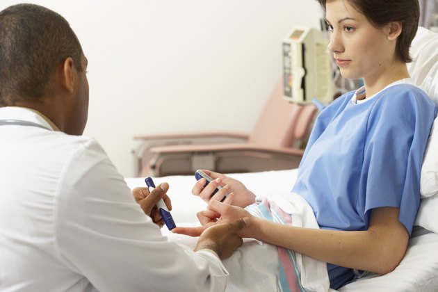 Rear view of a male doctor taking a blood sample from a female patient's finger