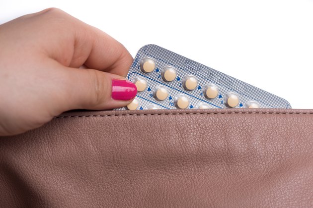 Woman hand pulling a contraceptive pills blister from a handbag