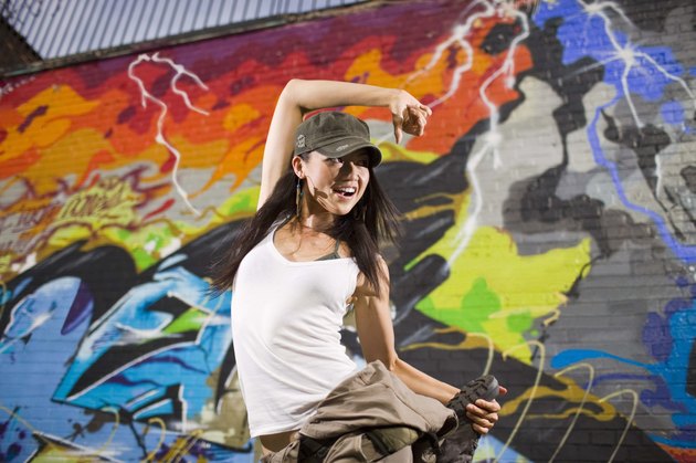 Woman street dancing by graffiti mural