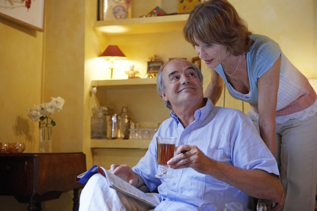 Mature couple relaxing in living room, woman at man's shoulder