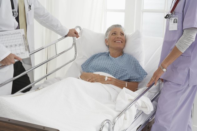 Patient in hospital bed speaking to Doctor and Nurse, smiling