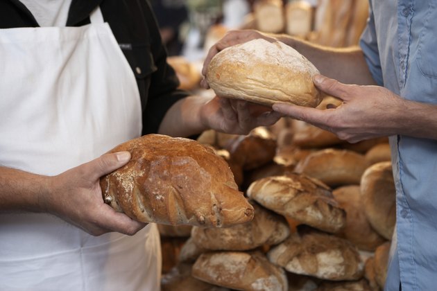 Market stallholder selling bread to customer, close-up