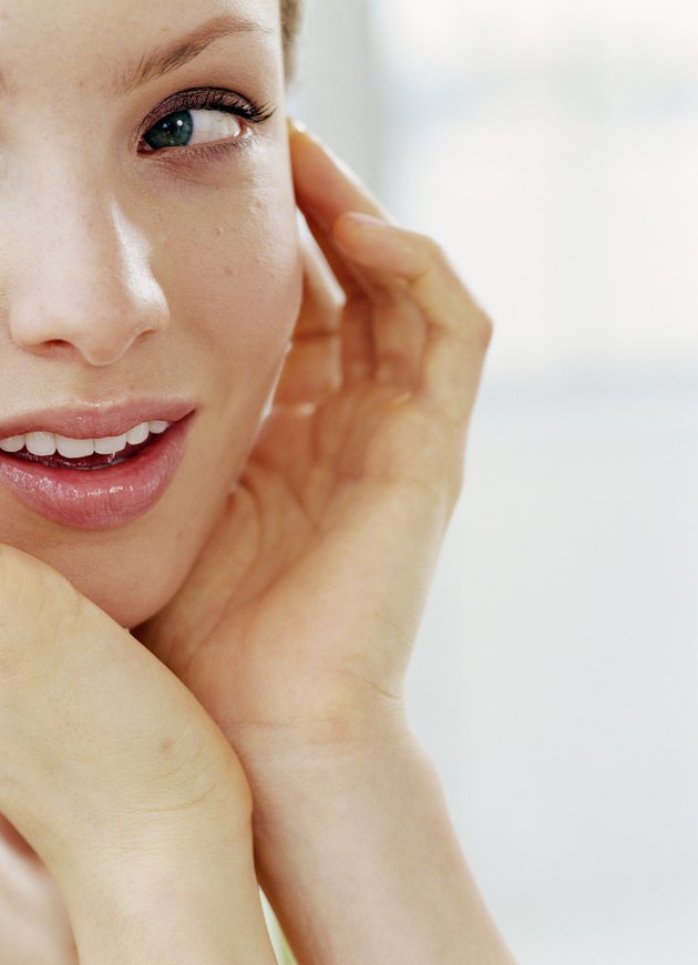 Young woman resting chin in hands, looking away, close-up