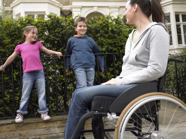 Mother in wheelchair in street with daughter and son (7-9) smiling