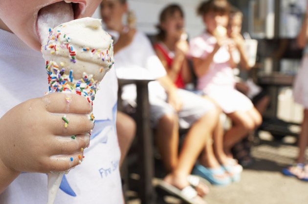 Boy (2-4) licking ice cream, close-up, other children in background