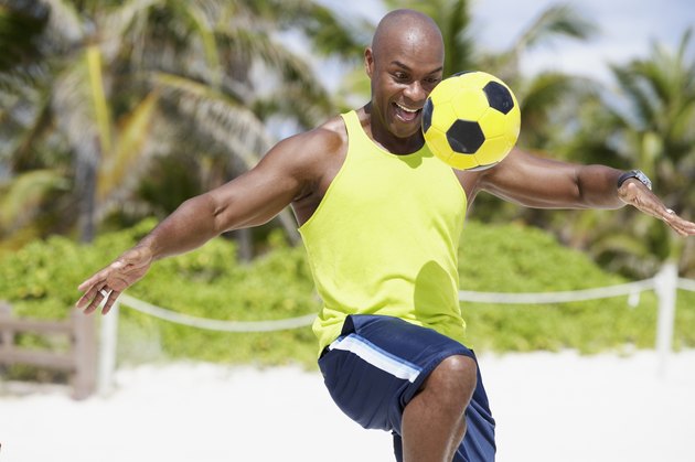 African American man bouncing soccer ball on knee
