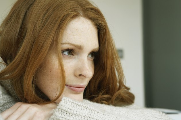 Young woman resting head on arms, looking away, close-up