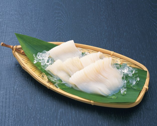 Fresh squid served on a bamboo basket with a leaf and ice cubes