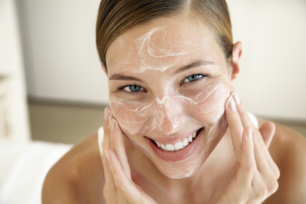 Smiling Young Woman Applying Face Cream
