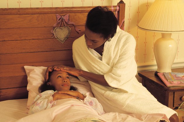 Mother caring for sick daughter in bed