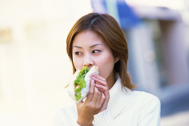 正在吃三明治的年轻成年妇女，前视图