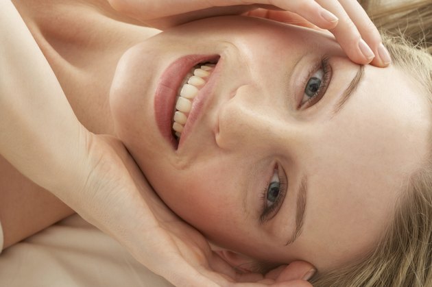 Young woman lying on bed, smiling, portrait, elevated view, close-up