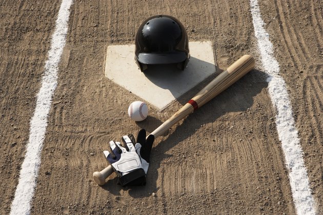 Baseball, bat, batting gloves and baseball helmet at home plate