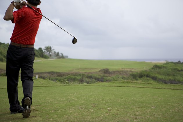 Man swinging golf club, rear view