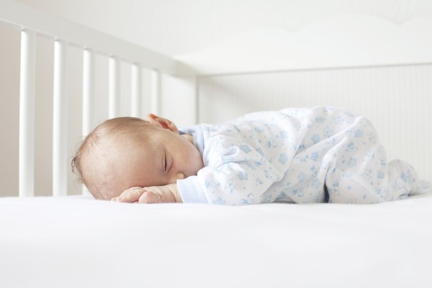 newborn lying on his tummy in crib