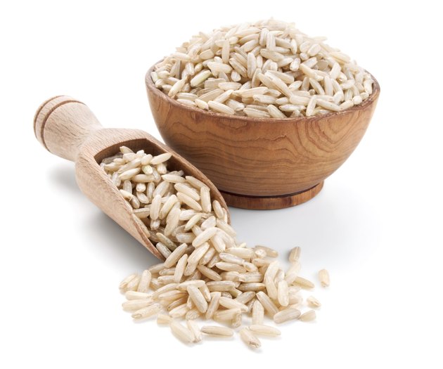 brown rice in a wooden bowl isolated on white