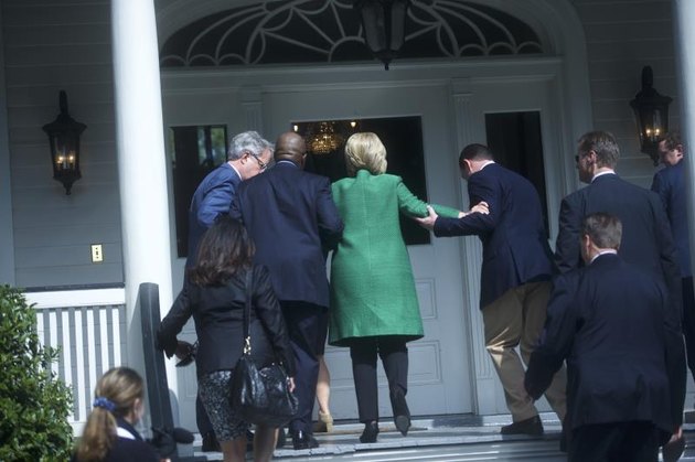 Campaign members assist Clinton up a small flight of steps.