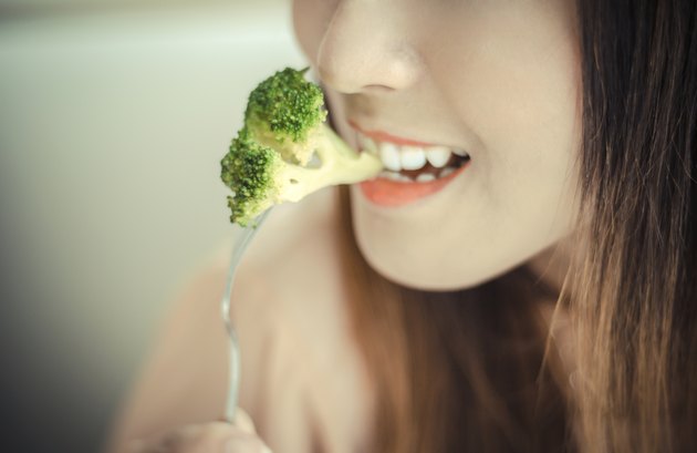 happy smiling woman eating broccoli