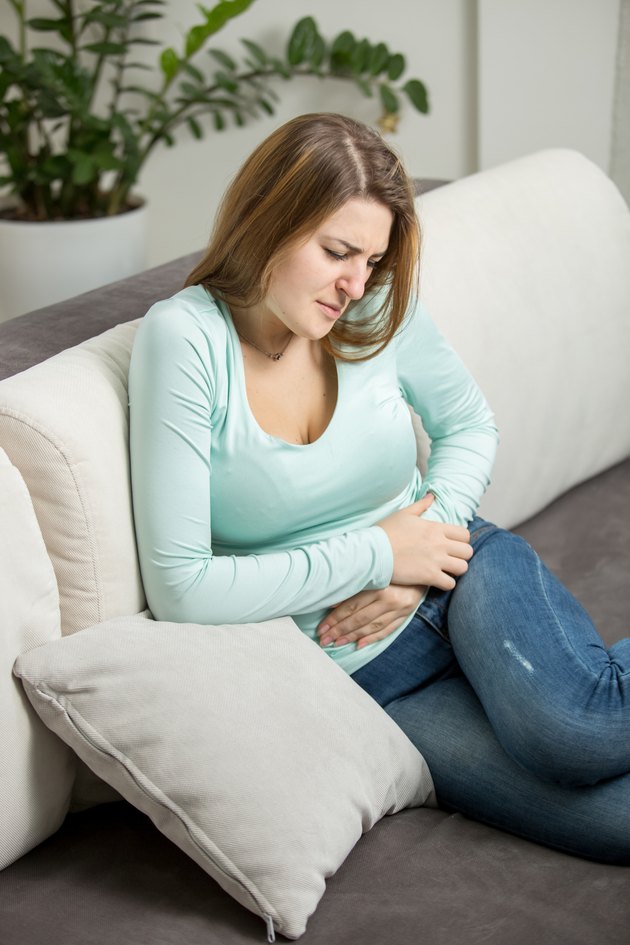 woman with abdominal ache sitting on sofa