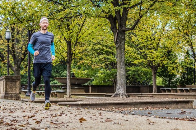 A young man runs solo in his local park.