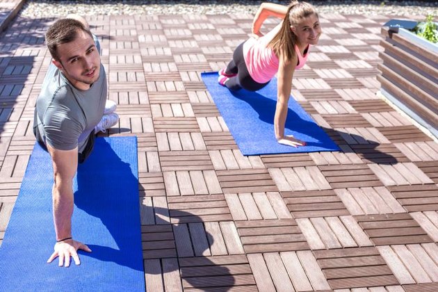Young couple doing together side plank exercise on the rooftop, outdoors.