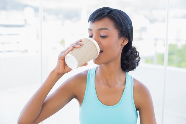 Pleased black haired woman drinking coffee