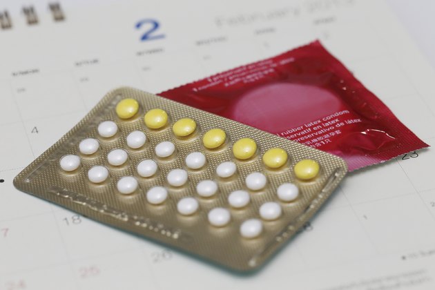 birth control pills with condom on a calendar