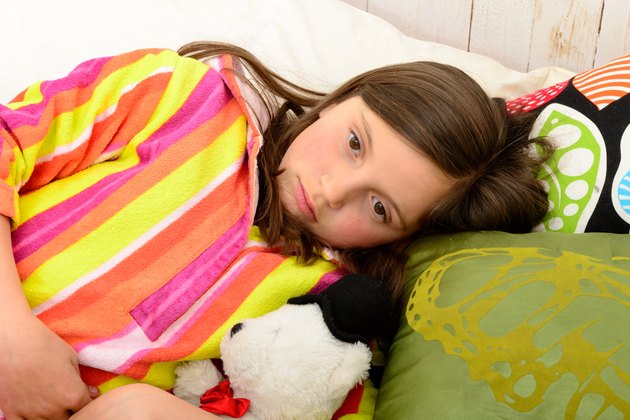little girl in her bed has a stomachache