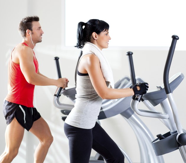 man and woman with elliptical cross trainer at gym