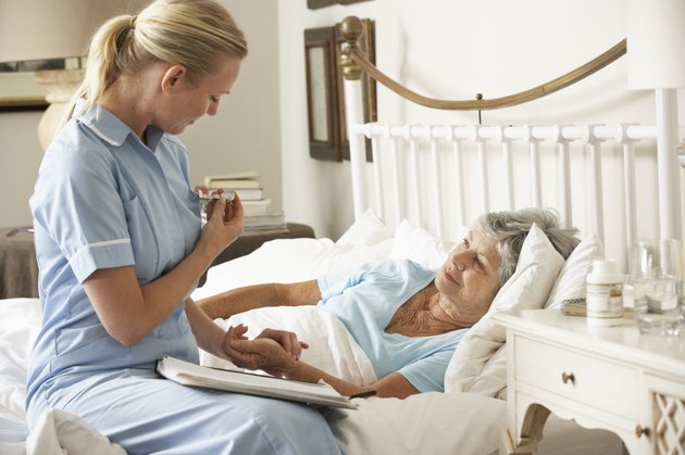 Nurse Taking Pulse Of Senior Patient In Bed