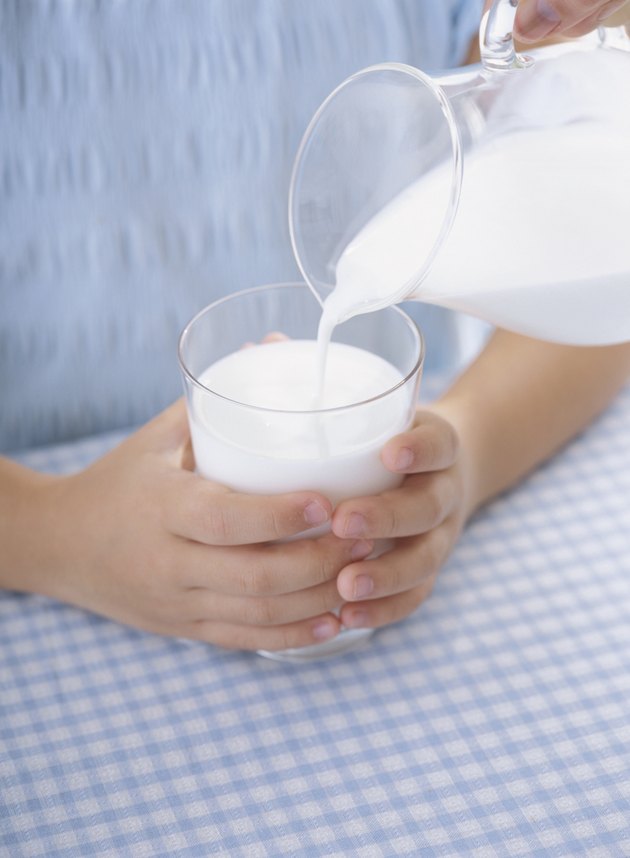 A child's hands holding a glass of milk