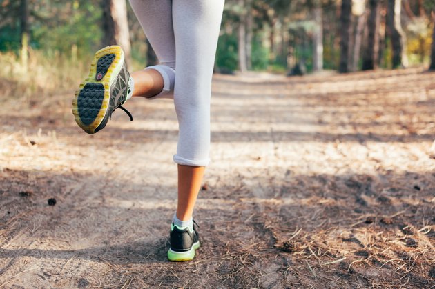 Runner feet running on road close-up on shoe. woman fitness