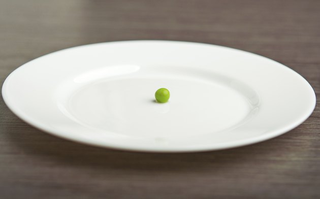 diet concept. one pea on an empty white plate