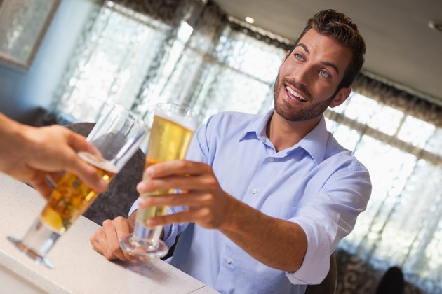 Smiling businessman clinking glass of beer with bartender