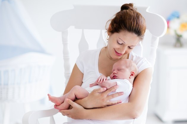 Young mother and newborn baby in white bedroom
