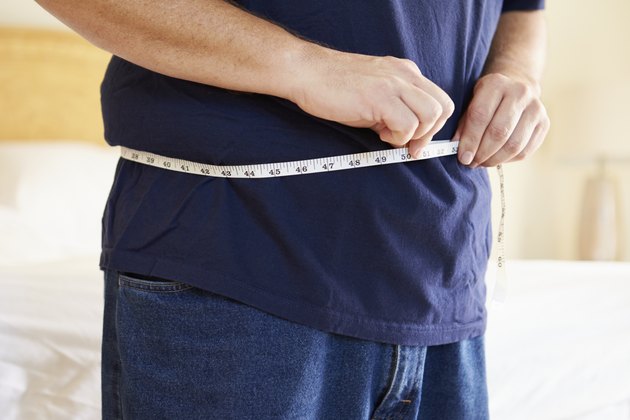 Close Up Of Overweight Man Measuring Waist