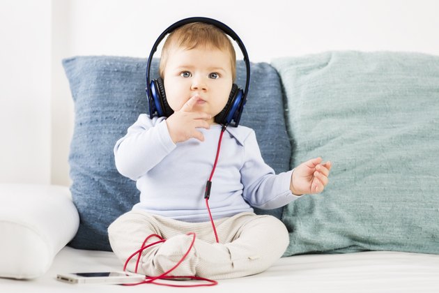 Adorable baby boy listening music at earphones.