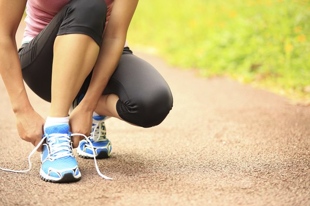 woman runner tying shoelaces on trail