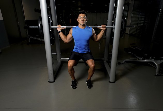 Fitness Trainer doing squats with barbells