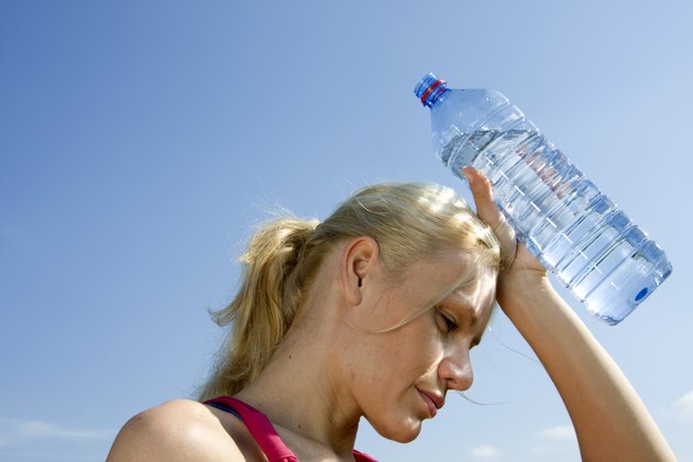Young woman holding bottle of water under blue sky
