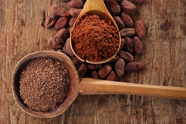 grated dark chocolate in old wooden spoon on roasted cocoa