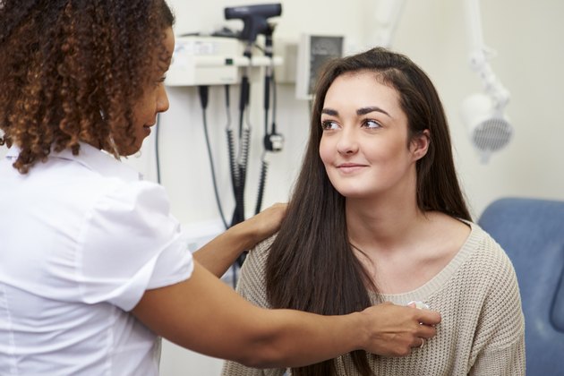 Female Consultant Examining Teenage Patient In Hospital