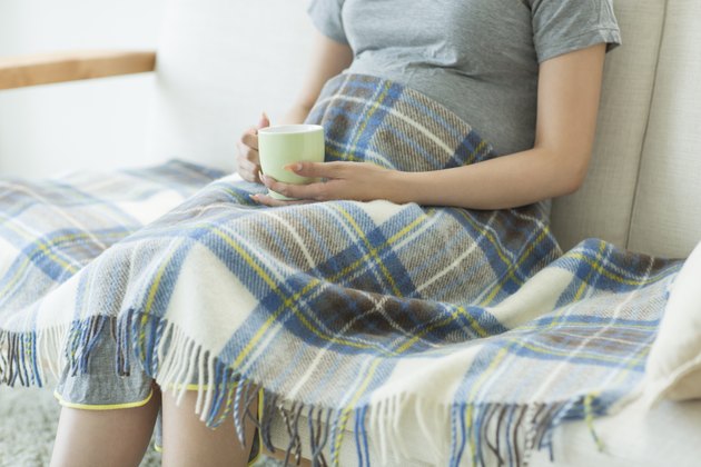 The pregnant woman who sits down on a sofa