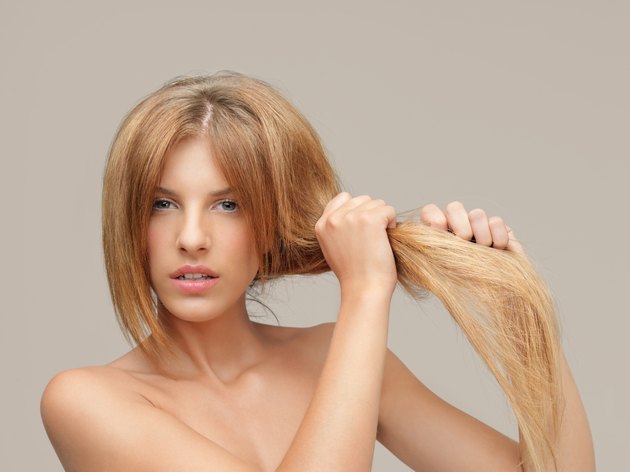 upset woman pulling dry hair split ends