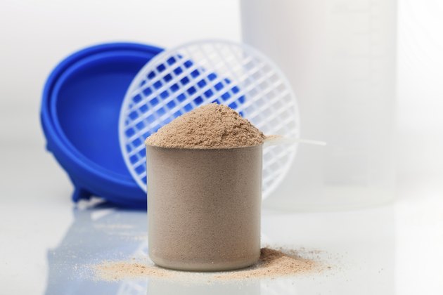 Chocolate whey isolate protein scoop in front of shaker